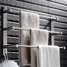 three towels hanging on a towel rack in front of a black wall with metal bars