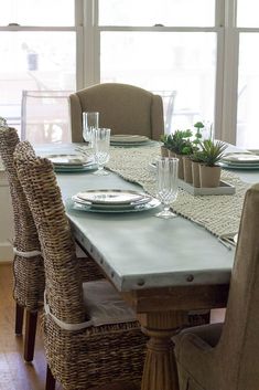 a dining room table with place settings and wicker chairs