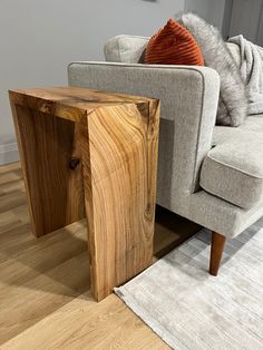 a wooden table sitting on top of a hard wood floor next to a gray couch