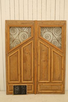 an open wooden door with a chalkboard attached to it's side and two doors that have metal designs on them