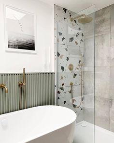 a white bath tub sitting next to a walk in shower under a framed picture on the wall