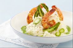 shrimp, asparagus and rice in a white bowl on a blue tablecloth