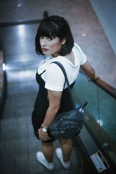 a woman is standing on an escalator with her purse