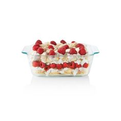 a glass casserole dish filled with fruit and whipped cream, on a white background