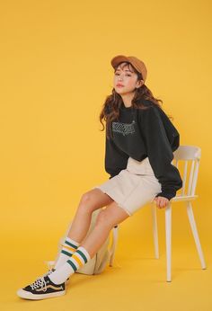 a young woman sitting on top of a white chair wearing a hat and socks with her legs crossed