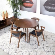 a dining room table with four chairs in front of two pictures on the wall behind it