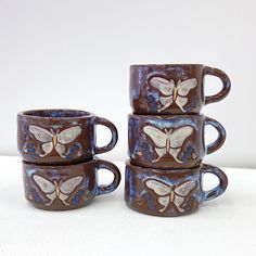 four coffee mugs with butterflies painted on them