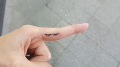 a person's finger with a small tattoo on it that has eyelashes sticking out of it