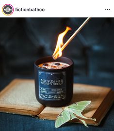 an open book sitting on top of a table next to a lit candle and a leaf