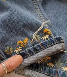 someone is stitching flowers on their jeans