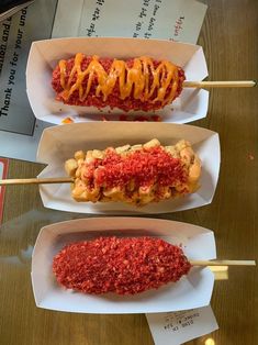 three different types of hot dogs on sticks with ketchup and mustard toppings