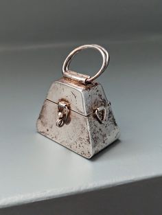 "Presenting this vintage, unusual sterling pill box shaped like a purse. It has a movable handle on top, handles on each side, and the clasp in front. Hinges and clasp work perfectly. No dents or other damage. There is some tarnish which can be polished for a more shiny look. The patina gives it a nice look.  What makes this piece special is its design and functionality. You can use it as a pill box and it displays well on the shelf. The handles (both top or side) can be used to attach to chain and wear this large piece as jewelry that can hold something small inside. Pills or something special. A wearable pill box!  Size: 1 1/2\" x 1\" x 1 3/4\" Marked 925 and initials on the inside. Made in Mexico  Thank you for looking! Feel free to reach me with questions and visit my shop for addition Collectible Metal Locket Necklace, Vintage Metal Locket Charm Necklaces, Vintage Handheld Box Bag With Detachable Handle, Vintage Sterling Silver Jewelry With Box Clasp, Antique Jewelry Gift With Box Clasp, A Pill, Silver Gift Wrap, Miniature Projects, Pill Boxes