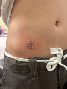 a woman's stomach with a clover tattoo on her lower side ribcage