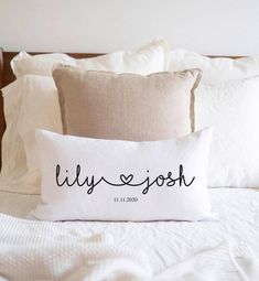 a pillow that says lilly joseph on it sitting on a bed with white sheets and pillows