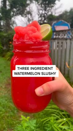 someone holding up a red mason jar filled with watermelon slushy