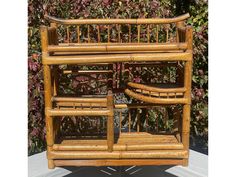 a bamboo shelf with two baskets on it and some plants in the back ground behind it