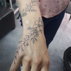 a person with a flower tattoo on their arm and hand is holding something in her other hand