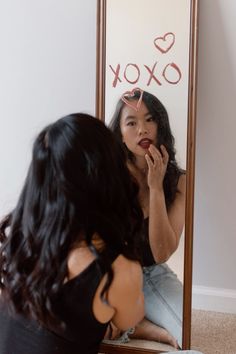 a woman sitting in front of a mirror brushing her teeth