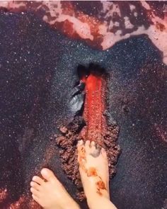 a person standing on top of a black sand beach