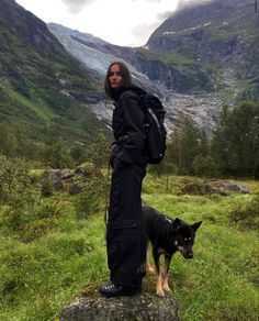 a woman standing on top of a rock next to a dog