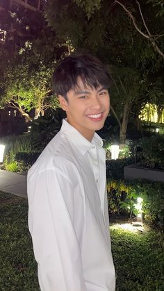 a young man standing in front of a tree at night with his hands on his hips