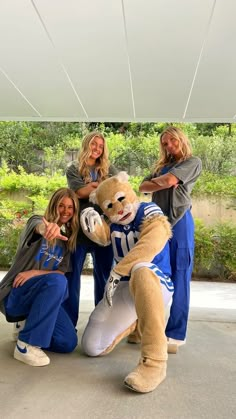 three women pose with a stuffed animal in front of them