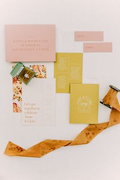 the wedding stationery is laid out on top of each other, including yellow and pink