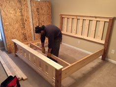 a man working on a bed frame in a room with unfinished walls and flooring