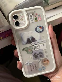 a person holding up a cell phone case with stickers on it's side