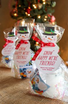 three snowmen are wrapped in plastic and sitting next to a christmas tree