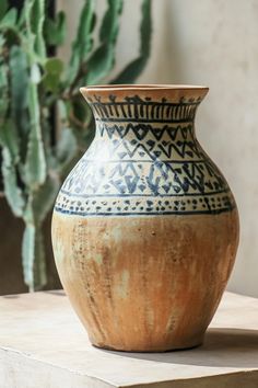 a vase sitting on top of a table next to a potted plant