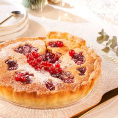 a pie with cranberries and powdered sugar sits on a glass platter