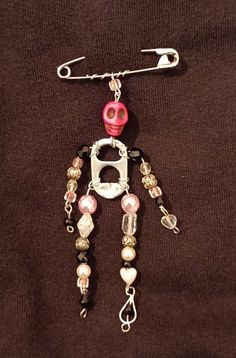 a pink and white beaded robot charm on a black shirt with silver chain attached to it