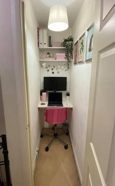 a small home office with a pink desk and computer on the top shelf in front of it