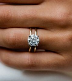 a woman's hand holding a diamond ring