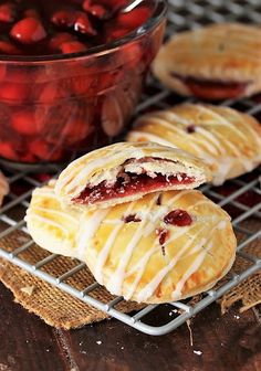 cherry hand pies on a cooling rack next to a bowl of cherries