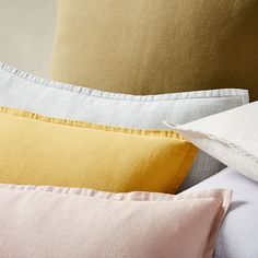 four pillows stacked on top of each other with different colored linens in the background