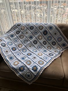 a blue and white blanket sitting on top of a brown couch next to a window