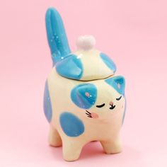 a blue and white cat cookie jar on a pink background