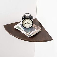 an alarm clock sitting on top of a wooden shelf next to some magazines and newspapers