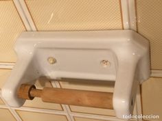 a white wall mounted toilet paper dispenser with a wooden roller attached to it