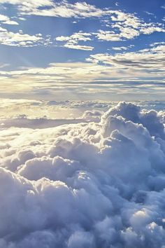 the view from an airplane looking down on some clouds and blue sky with white puffy clouds