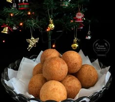 a glass bowl filled with donuts next to a christmas tree