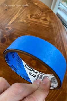 a person is holding a blue tape on top of a wooden table