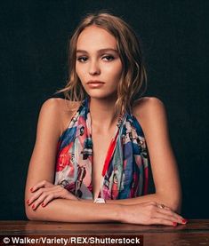 a beautiful young woman sitting at a table with her arms folded over her chest and looking into the camera