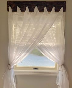 a window with sheer curtains and potted plants