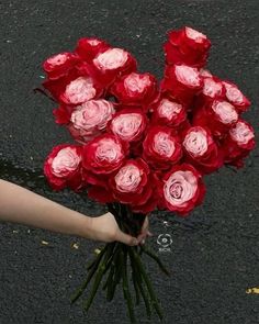 a person holding a bouquet of roses in their hand on the street with other flowers