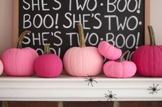 some pink pumpkins are sitting on a mantle