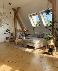 a cat sitting on the floor next to a couch in a room with wooden floors