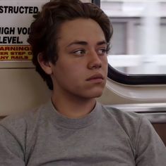 a young man sitting next to a window on a train